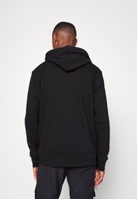 Sudadera con capucha negra de corte relajado, que cuenta con una gran capucha, puños acanalados y dobladillo en la cintura, fabricada con una suave mezcla de algodón.