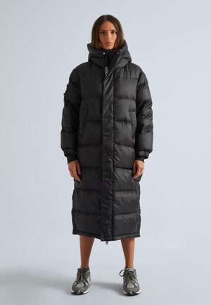 Schwarze Pufferjacke mit langer Silhouette, großem Kapuzen und Reißverschluss. Hergestellt aus glänzendem Material mit horizontal gesteppten Abschnitten und seitlichen Taschen.