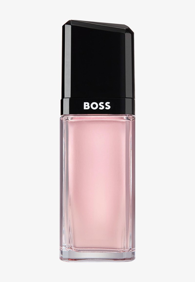 Flacon en verre rectangulaire avec un liquide rose pâle et un bouchon noir portant l'étiquette "BOSS", probablement un parfum ou un produit cosmétique.