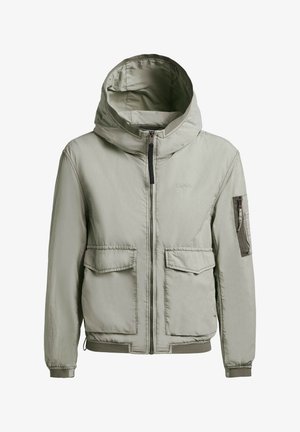 Világosszürke kapucnis dzseki elülső cipzárral, két takarófüles zsebbel, egy cipzáras ujjzsebbel, valamint bordázott mandzsettákkal és szegéllyel.