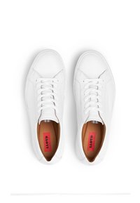 Białe skórzane sneakersy o gładkim wykończeniu, zaokrąglonym czubku, płaskich sznurowadłach oraz beżowym wnętrzu z czerwonym logo.