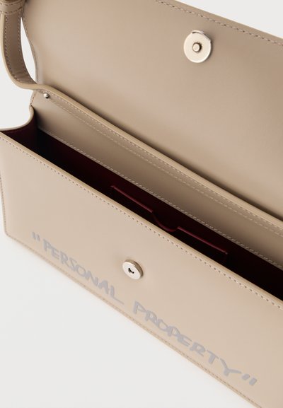 Μπεζ ορθογώνια δερμάτινη τσάντα χειρός με ασημένιο κούμπωμα κουμπί και κείμενο "ΠΡΟΣΩΠΙΚΗ ΙΔΙΟΚΤΗΣΙΑ" τυπωμένο με γκρι χρώμα στην εμπρόσθια πτυχή.