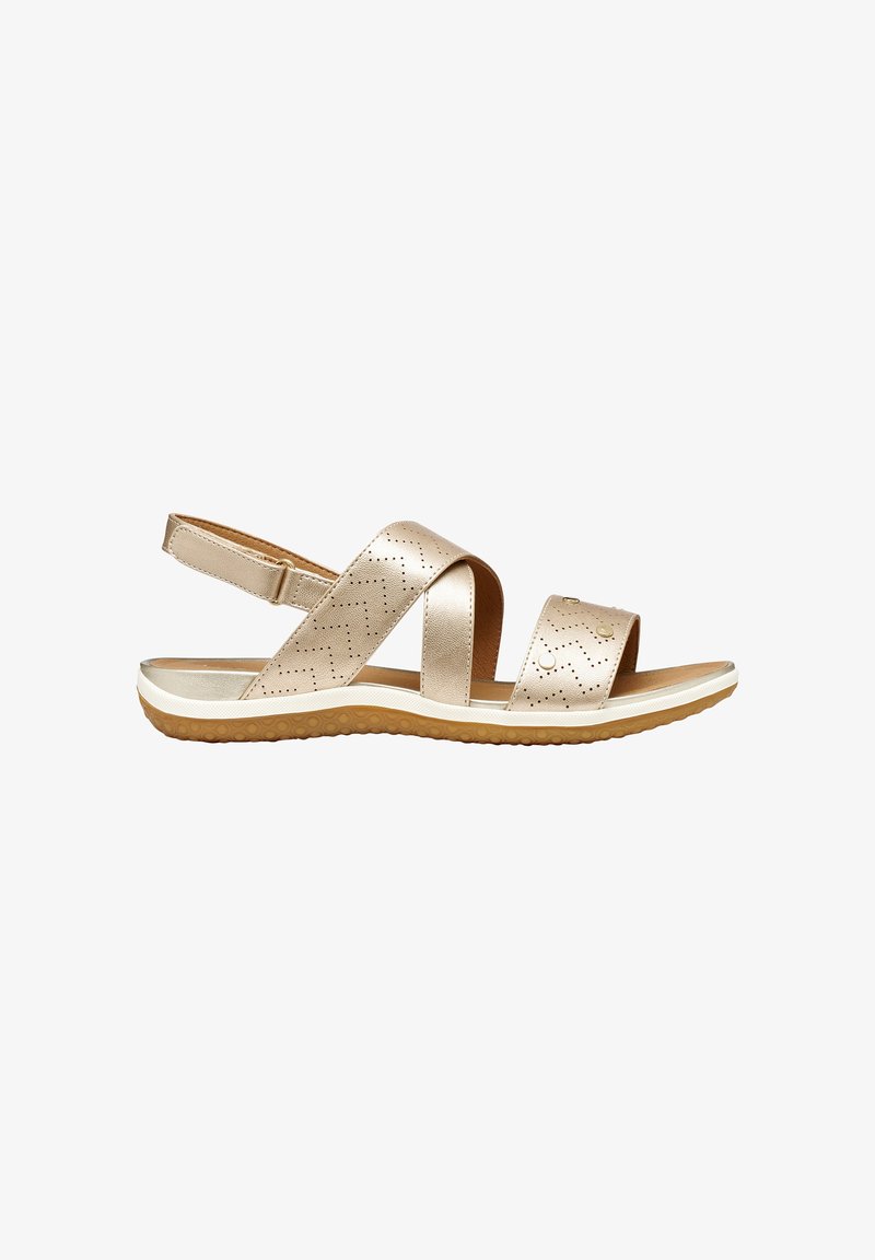 Sandale beige à bout ouvert avec brides perforées en zigzag, bride arrière ajustable, et semelle blanche rembourrée avec dessous marron texturé.
