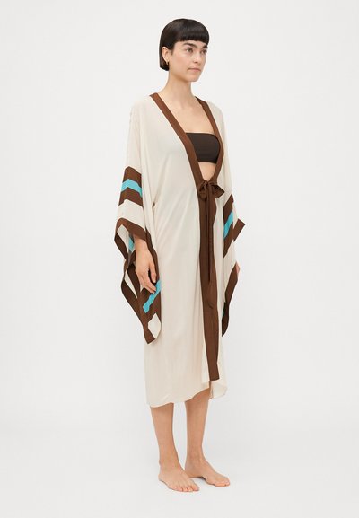 Robe en crème légère avec des accents rayés marron et turquoise. Comprend de larges manches et une ceinture à la taille. Texture douce et fluide.