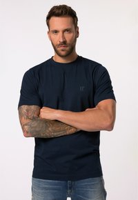 Marinblå bomulls t-shirt med rund hals, korta ärmar och subtil "JP"-logotyp på bröstet, kombinerad med slitna blå jeans.