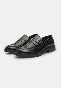 Zwarte gepatineerde leren loafers met een gladde afwerking, een verhoogde naadtoets aan de voorkant en een lage, platte hak voor comfort.