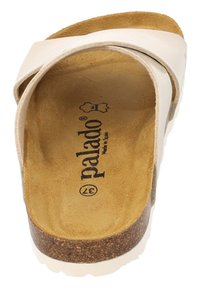 Chancla deslizante de color beige pálido con plantilla de corcho, parte superior de cuero suave y diseño minimalista. Presenta un logo 'palado' en su interior.