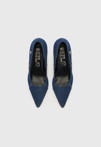 Chaussures en denim à bout pointu de couleur bleu foncé avec une silhouette élancée et un intérieur noir. Présentent des accents cousus et un petit détail de logo.