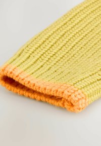 Kootud randme soojendaja helesinises toonis oranži soonikkoega. Omab tekstuurset mustrit ja pehmet, mugavat kangast.