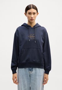 Sweatshirt azul-marinho feito de tecido suave, com um bolso frontal, capuz com cordão e logótipo da Calvin Klein em dourado no peito.