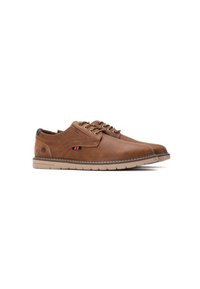 Zapatos de cuero marrón con un acabado liso, punta redondeada y suela de goma crema. Cuentan con cordones y un pequeño detalle de logo en azul y rojo.