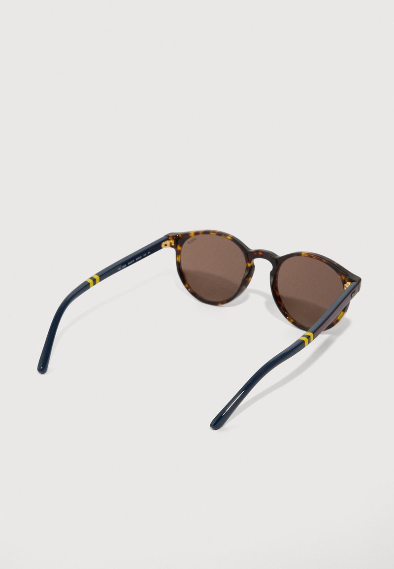 Round tortoiseshell sunglasses with dark brown lenses and navy blue temples featuring yellow stripes on white background.