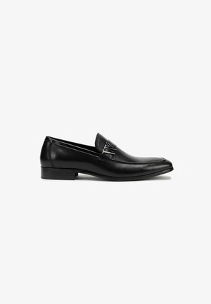 Black leather loafers with a sleek design, featuring a smooth texture, pointed toe, and decorative hardware on the front.