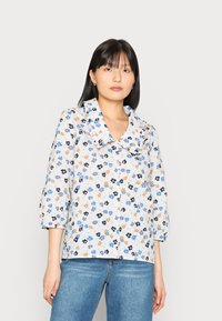 Camisa de botão floral em tecido leve com padrões em azul, laranja e preto. Apresenta um colarinho grande e mangas três quartos.