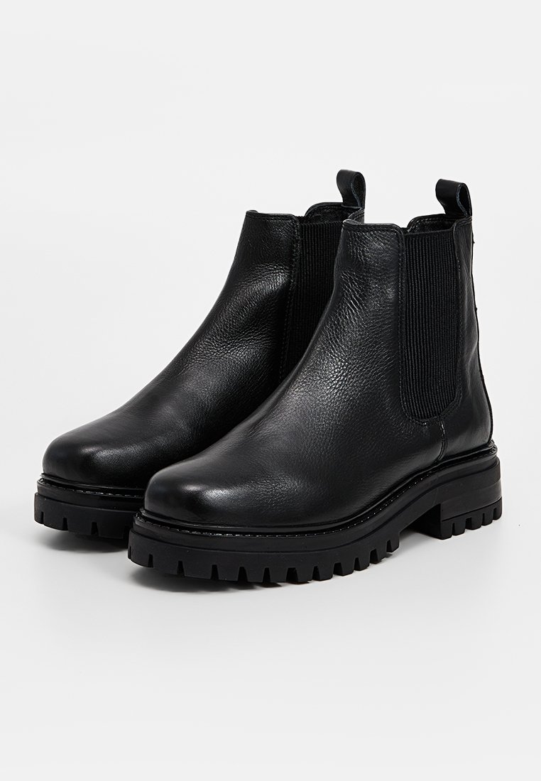 Bottines en cuir noir avec une surface texturée, des panneaux latéraux élastiques et des semelles épaisses et robustes pour une bonne adhérence. Bride de tirage à l'arrière.