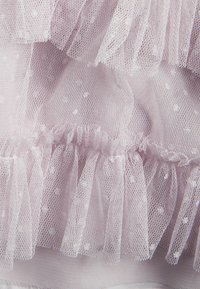 Lavendel tulle-tyg med prickar, lager av rullor och en mjuk texturerad yta. Kanterna är råa med en lätt och luftig look.