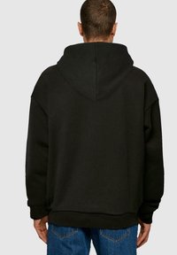 Melnā pārmērīgā džemperis ar lielu kapuci, mīksta auduma, ar nolaižamām plecu daļām un ribotām aprocēm. Minimalistisks dizains bez redzamām rakstiem vai logotipiem.