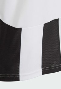 Weißes und schwarzes Sporttrikot mit einer Netzstruktur und kontrastierenden, einfarbigen Elementen. Die Nähte sind am Saum sichtbar.