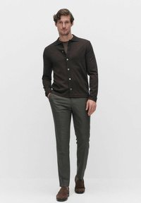 Bruin button-up cardigan van wol, gecombineerd met op maat gemaakte grijze pantalon en bruine schoenen. Slim fit ontwerp met subtiele texturen.