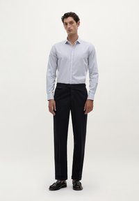 Cămașă cu dungi albastre deschise și albe, cu guler, combinată cu pantaloni negri de marină închisă și pantofi negri; material neted și croială ajustată.
