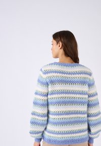 Maglione lavorato a maglia in blu chiaro, verde e strisce bianche. Presenta una vestibilità ampia, scollo rotondo e un motivo testurizzato. Materiale morbido e soffice.