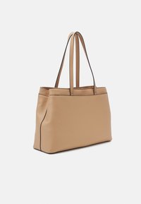 Beige kožená taška přes rameno se strukturovaným tvarem, dvěma dlouhými uchy a černými akcenty podél švů. Hladký povrch a minimalistický design.