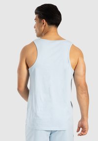 Lichtblauw katoenen tanktop met een ronde halslijn, brede armsgaten en een relaxte pasvorm. Gladde textuur en eenvoudig, minimalistisch ontwerp.