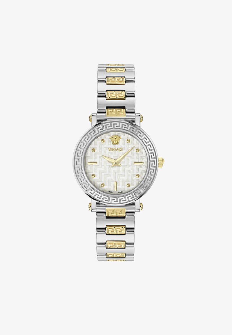 Sudraba un zelta tonī tērauda pulkstenis ar apaļu seju, baltu rakstainu ciparnīcu un grieķu atslēgas dizaina aksesuāriem uz rokassprādzes.