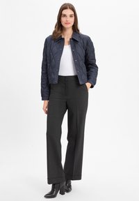 Marineblauwe gewatteerde jas met een kraag, gecombineerd met zwarte hoge taille broeken en zwarte haklaarzen. Gladde textuur, casual pasvorm.