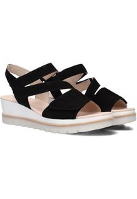 Zwarte suède wedge sandalen met meerdere kruislings gespen, open teen ontwerp en een witte rubberen zool met een gestructureerde afwerking.