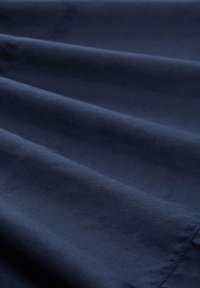 Tessuto blu navy con una texture liscia, caratterizzato da morbide pieghe e una lucentezza uniforme, adatto per abbigliamento o rivestimenti.