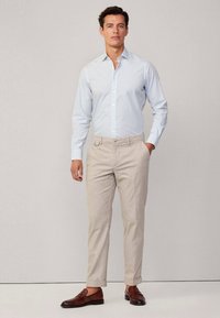 Himmelblau gestreiftes Hemd mit langen Ärmeln, kombiniert mit beigen Hosen und braunen Slippern. Glattes Material und maßgeschneiderte Passform.