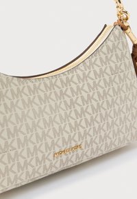 Μπεζ τσάντα hobo με επαναλαμβανόμενο μοτίβο λογοτύπου. Μετάλλικα στοιχεία σε χρυσό τόνο και κλείσιμο με φερμουάρ. Λεία υφή με καμπύλη σιλουέτα.