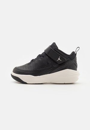 Baskets de sport noires pour enfants avec une semelle blanche, un design perforé et une bride ajustable avec un logo Jumpman sur le côté.