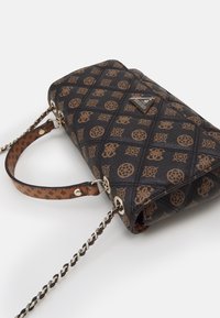 Czarna pikowana torebka z brązowymi akcentami w wzory, z łańcuszkowym paskiem i logo. Skórzany materiał z dekoracyjnymi motywami.