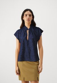 Blusa blu navy a maniche corte con motivo floreale testurizzato, scollatura a oblò, colletto arricciato e una vestibilità leggermente ampia.