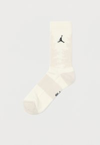 Meias brancas de crew com textura canelada, listras em bege claro e um logo preto da Jordan no lado externo. Material macio e atlético.
