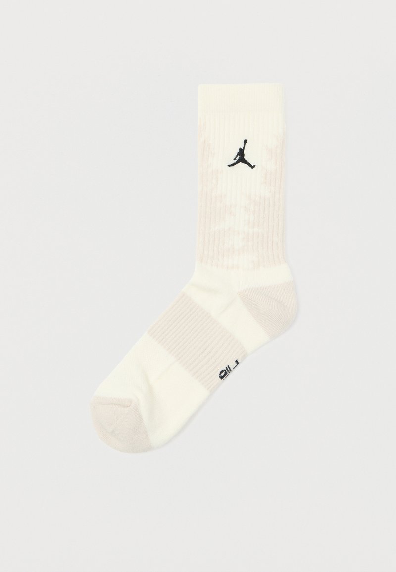 Meias brancas de crew com textura canelada, listras em bege claro e um logo preto da Jordan no lado externo. Material macio e atlético.