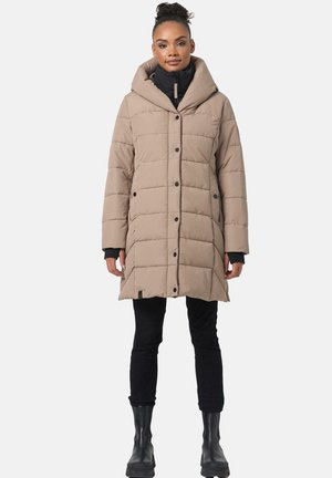 Beige pufferjas met capuchon, voorzien van een gestikte design, zwarte knopen en geribde manchetten, gedragen over zwarte broeken en chunky zwarte laarzen.