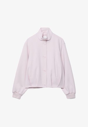 Veste boutonnée rose pâle avec col montant, manches longues, poignets côtelés et deux poches verticales à l'avant, posée à plat sur fond blanc.