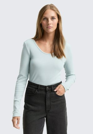 Lichtblauw ribbelshirt met lange mouwen en een ronde halslijn, gecombineerd met hoge taille zwarte spijkerbroek; gladde textuur en strakke pasvorm.