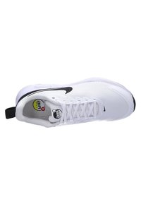 White Nike Air Max sneakers with a mesh upper, black swoosh, textured sole, and a pull tab at the heel. Circular logo on tongue.