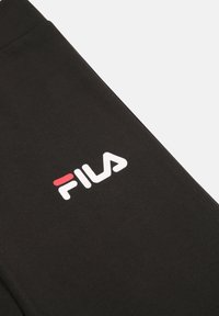 Pantalones de chándal negros de algodón con un logo de Fila en blanco y rojo. La tela tiene una textura suave y un ajuste cómodo y relajado.