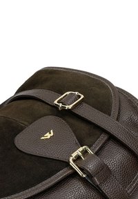 Ciemnobrązowa skórzana torebka z zamszu, z złotymi klamrami i małym złotym emblematem na skórzanym klapce.