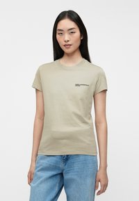 Beżowa bawełniana koszulka z krótkim rękawem, okrągłym dekoltem, z małym czarnym logo "KARL LAGERFELD JEANS" na lewej piersi. Klasyczny krój.