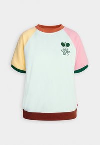 Lyhythihainen collegepaita vaaleansinisenä, jossa on moniväriset raglan-hihat. Paita sisältää vihreän logopainatuksen ja ruskean helman alaosassa.