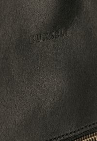 Zwart leer met een gestructureerde afwerking heeft een geperst "BURKELY" logo. Het oppervlak lijkt zacht met subtiele variaties in glans.