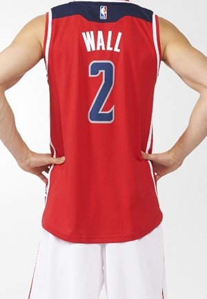 Person trägt ein rotes Basketballtrikot mit dem Namen "WALL" und der Nummer 2 auf dem Rücken, die Hände auf die Hüften gestützt, kombiniert mit weißen Shorts.