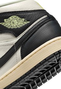 Gros plan sur le talon de la chaussure Air Jordan noir et blanc montrant le logo ailes Air Jordan embossé et la semelle texturée.