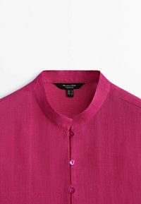 Magenta linen blouse featuring a mandarin collar, front button closure with matching buttons, and a textured fabric surface.
